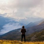 A lone hiker stands in awe of the misty mountain landscape in France.